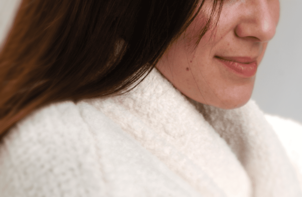 Woman wearing a cozy white sweater, smiling.