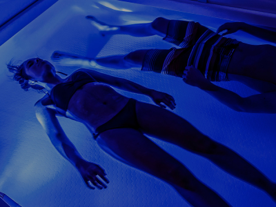 People floating in a blue lit tank.