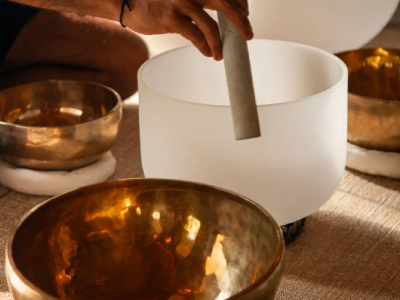 Hand playing crystal singing bowl and gongs.