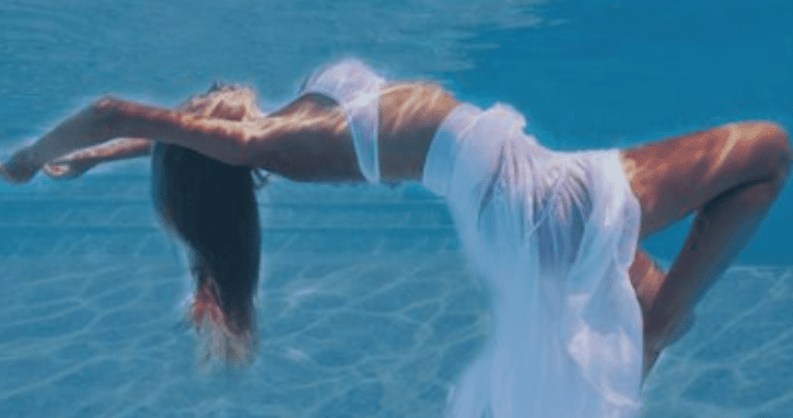 Woman floating underwater in flowing white dress.