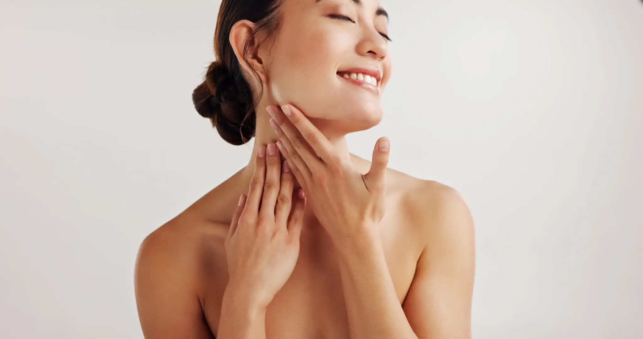 Smiling woman touching her neck, relaxed pose.